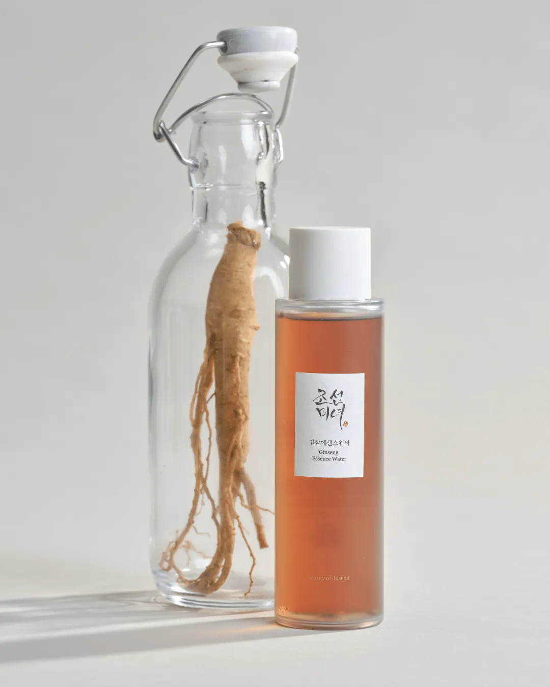 Ginseng Essence Water junto a una botella con raíz de ginseng