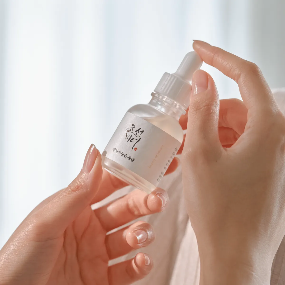 Manos sosteniendo el Glow Deep Serum con su gotero